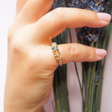 Hand holding a bundle of lavender with a gold ring and bracelet on a light background