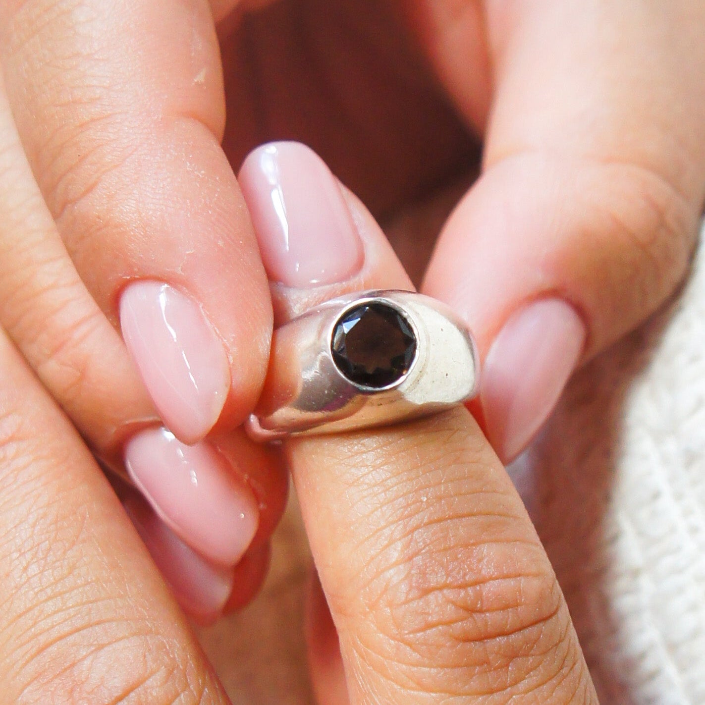 Close-up of a hand wearing a silver ring with a black gemstone.