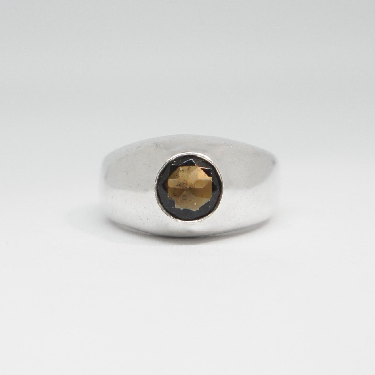 Silver ring with a dark gemstone on a white background