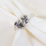 Silver ring with heart-shaped gemstones on a white fabric background