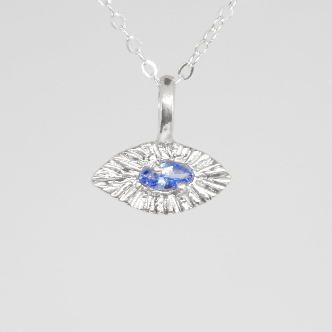 Silver pendant with a blue gemstone on a white background