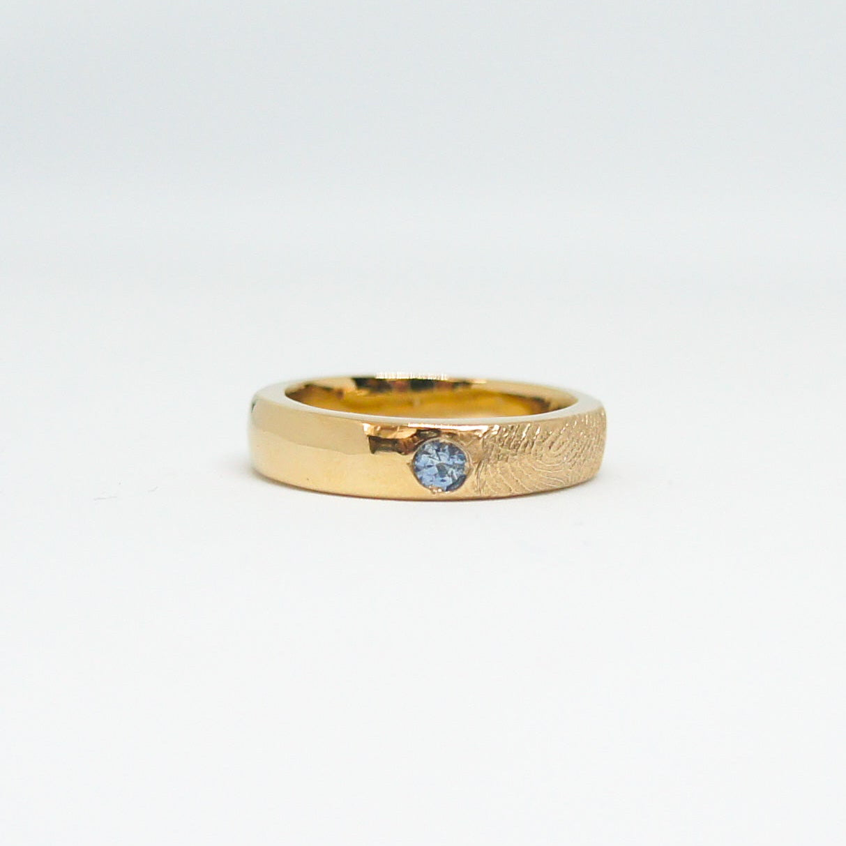 Gold ring with a blue gemstone on a white background