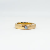 Gold ring with a blue gemstone on a white background