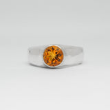 Silver ring with a yellow gemstone on a white background