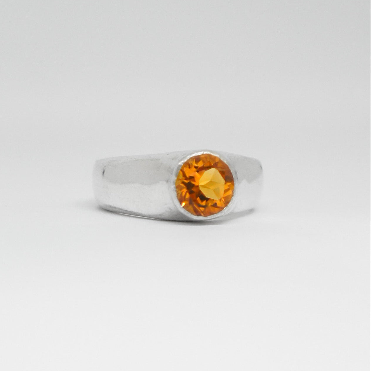 Silver ring with a yellow gemstone on a white background