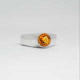 Silver ring with a yellow gemstone on a white background