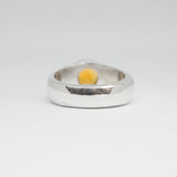 Silver ring with a yellow stone on a white background