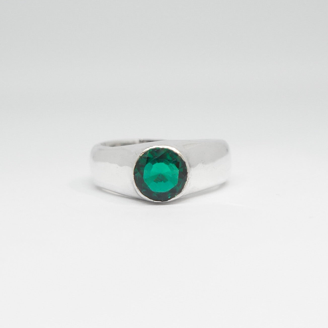 Silver ring with a green gemstone on a white background