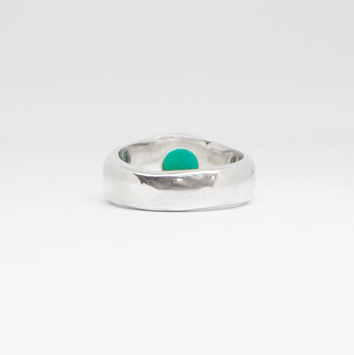 Silver ring with a emerald stone on a white background