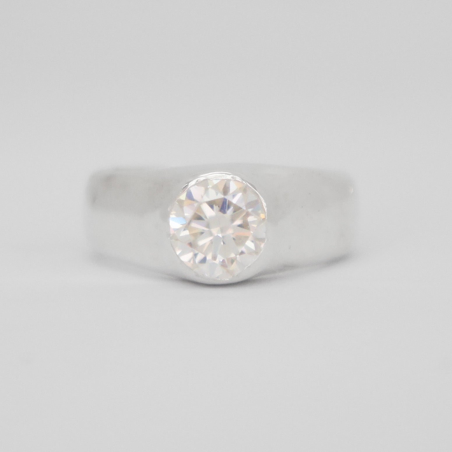 Silver ring with a diamond on a light gray background