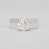 Silver ring with a diamond on a light gray background