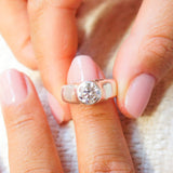 Close-up of a hand wearing a diamond ring with a blurred background