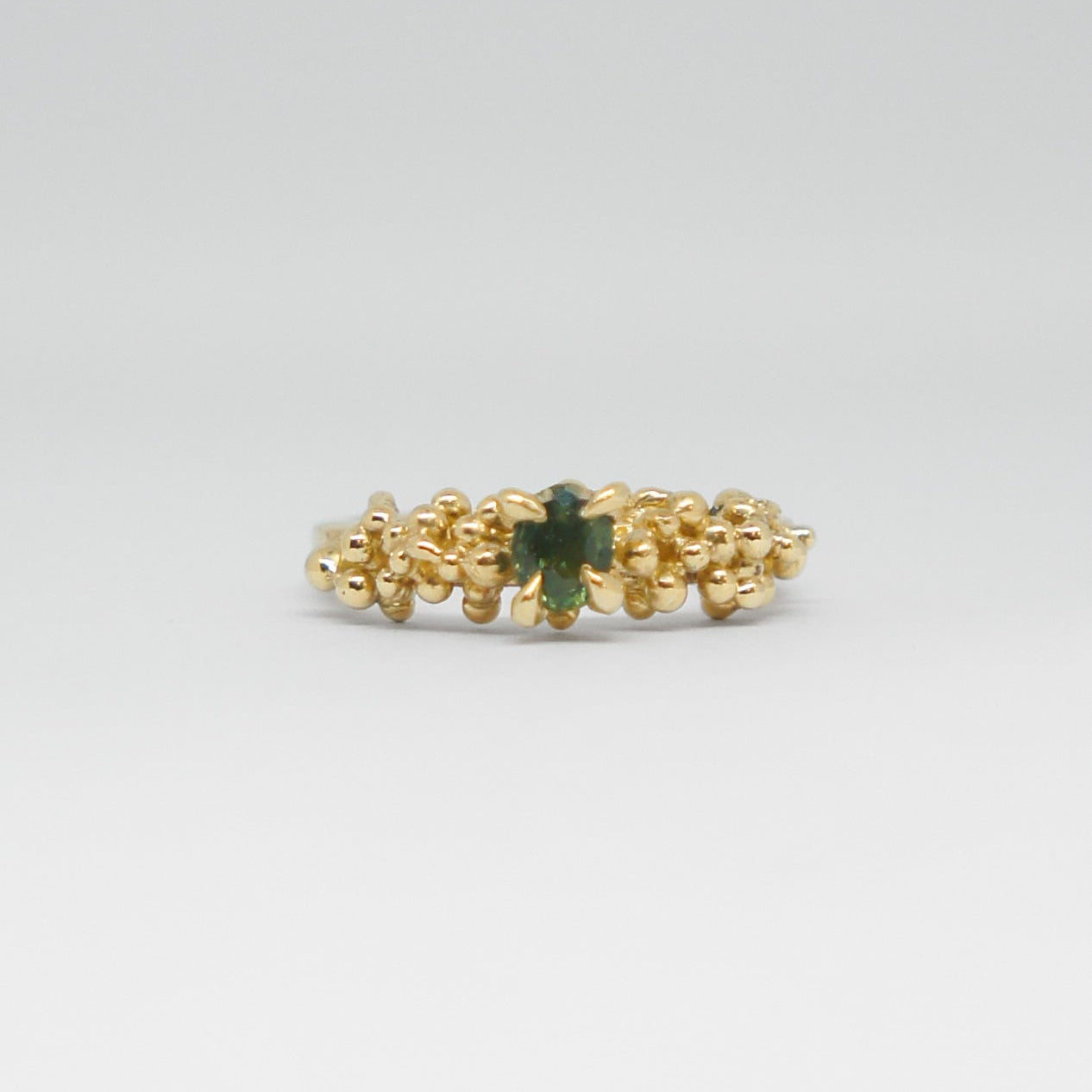 Gold ring with a green gemstone on a white background