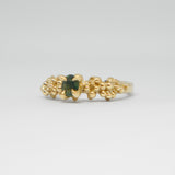 Gold ring with a green gemstone on a light gray background