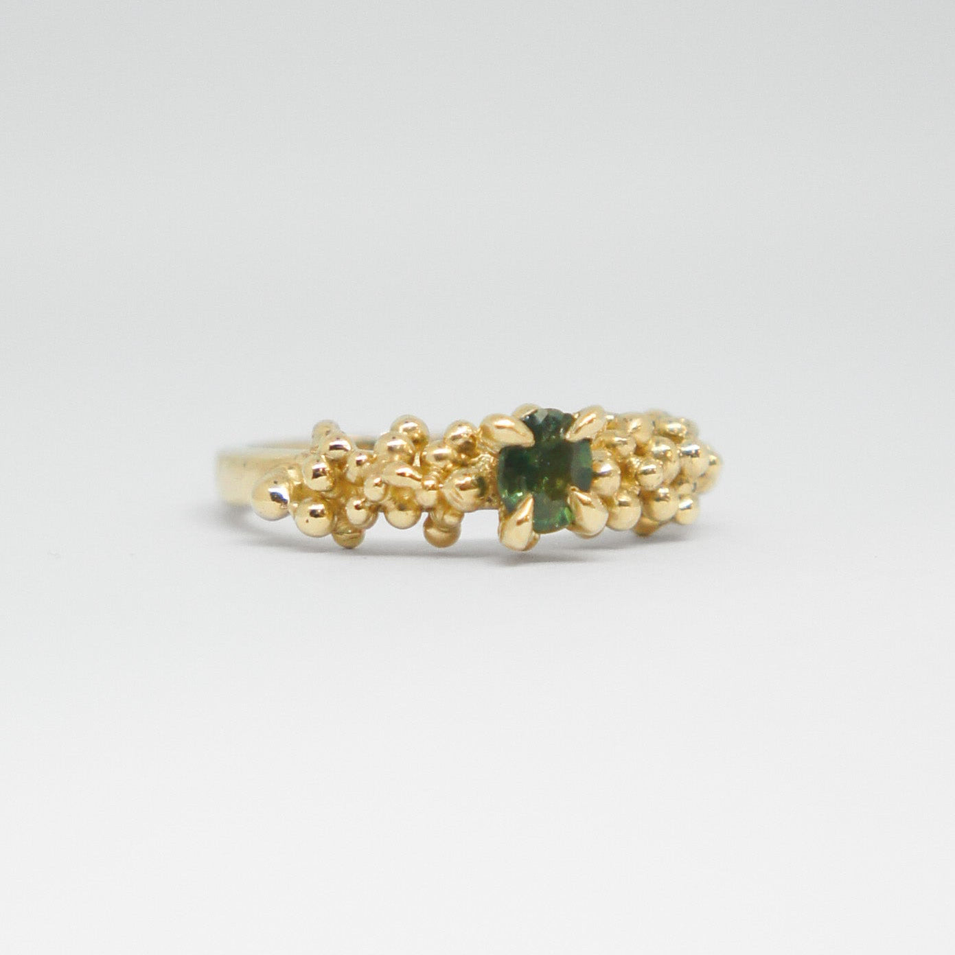 Gold ring with a green gemstone on a white background
