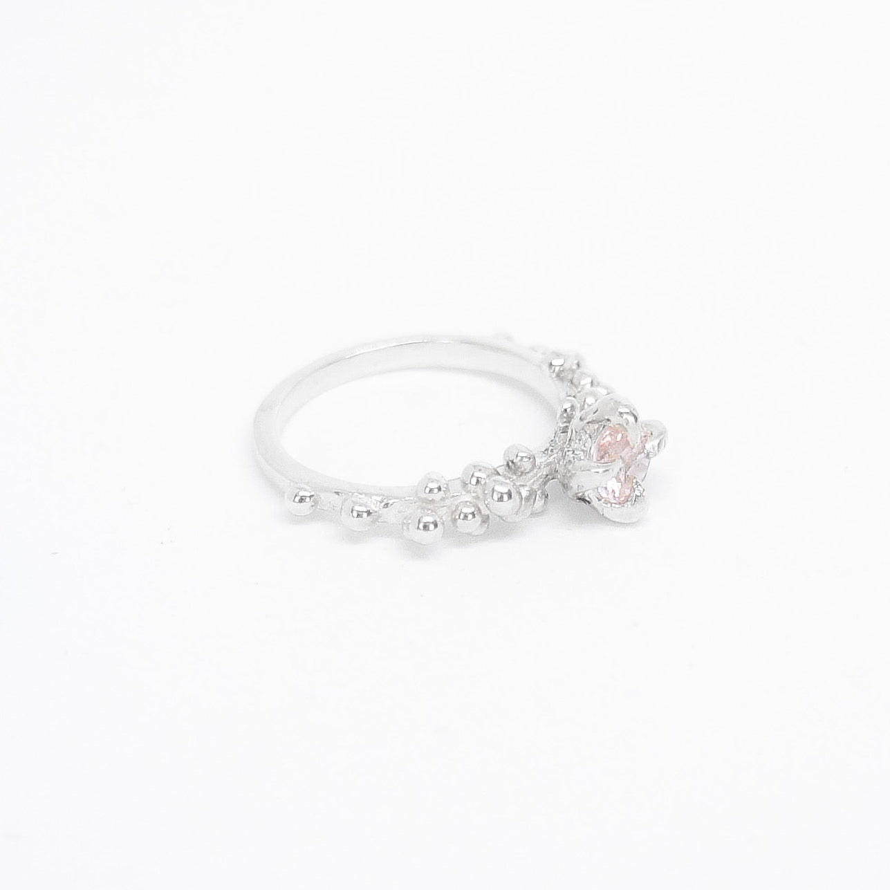 Silver ring with a small pink gemstone on a white background