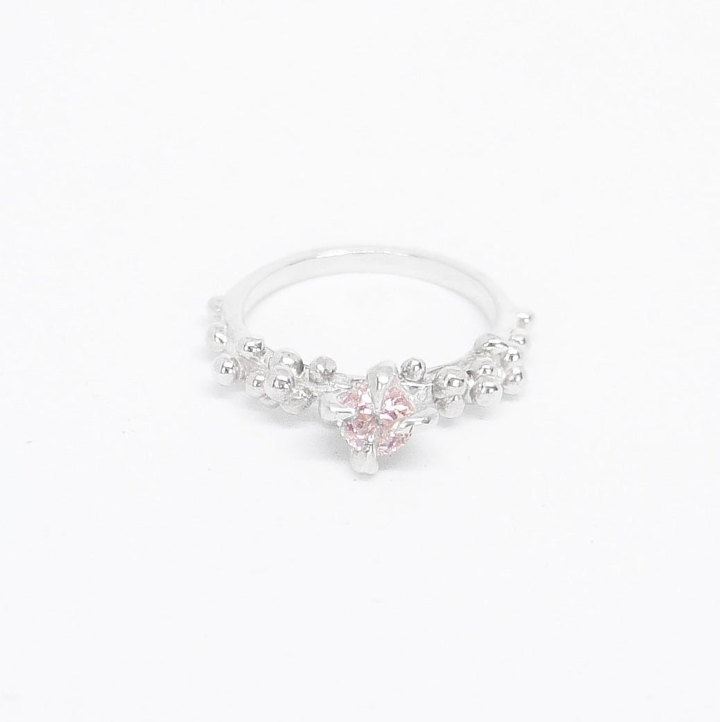Silver ring with pink gemstone on a white background