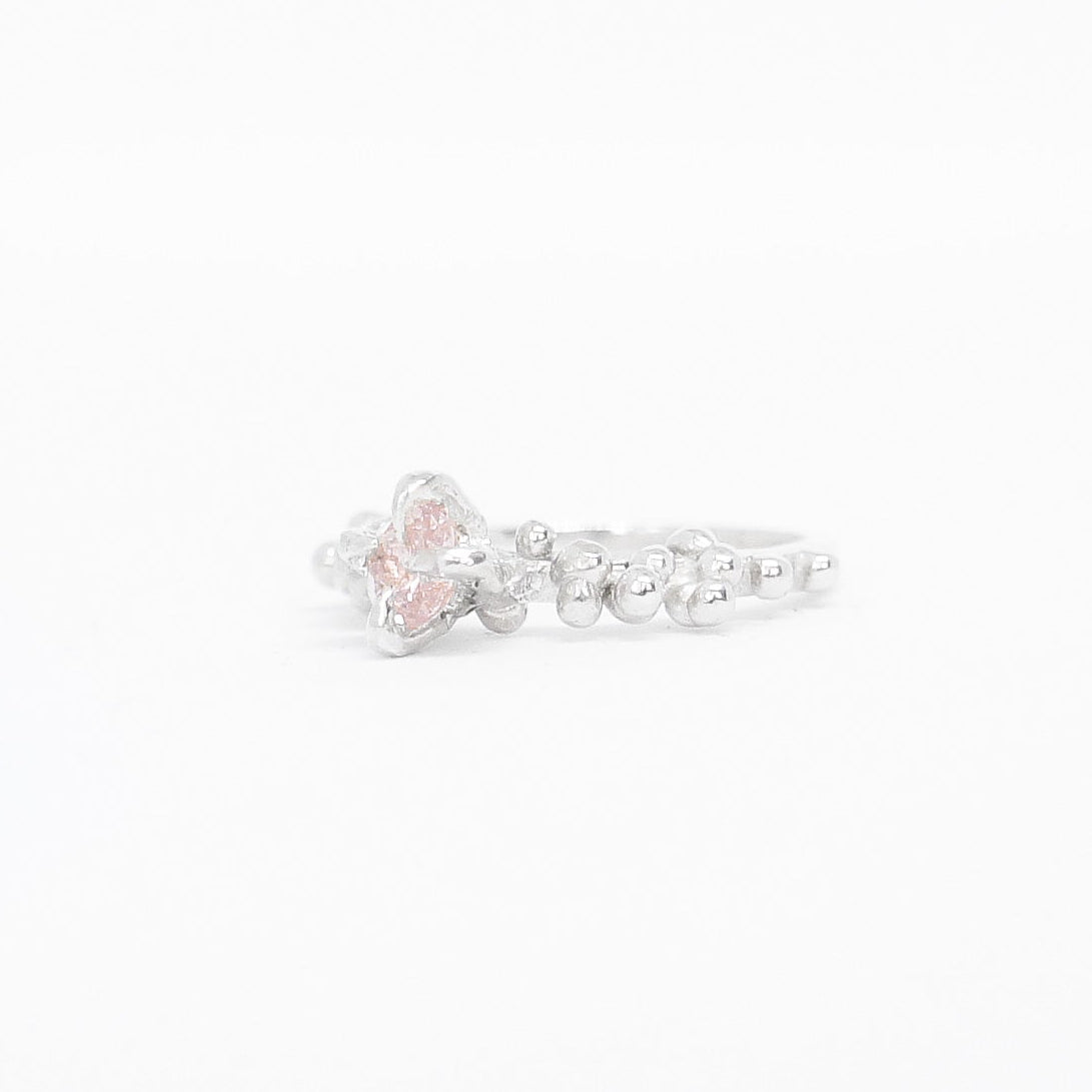 Silver ring with a pink gemstone on a white background