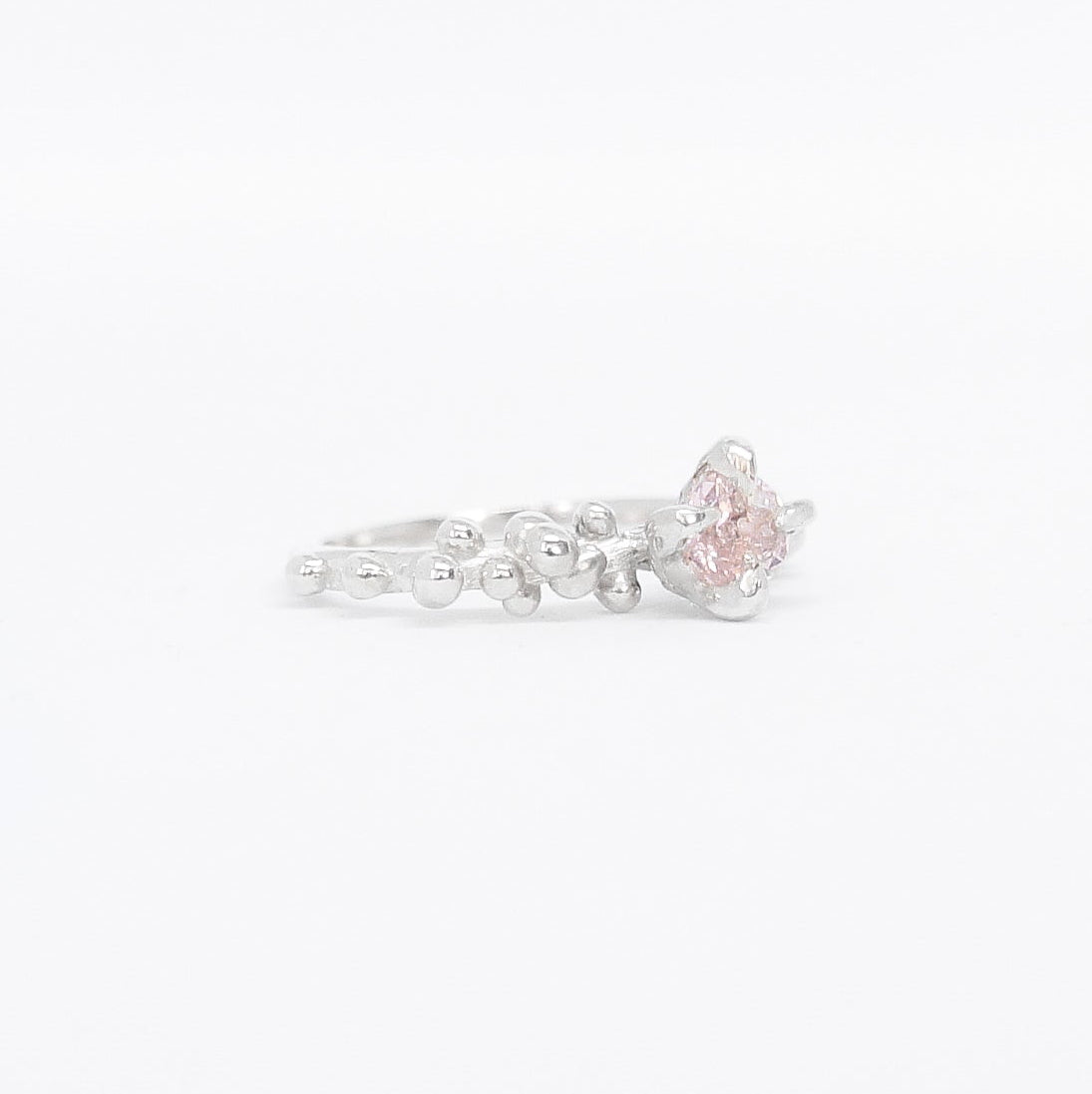 Silver ring with a pink gemstone on a white background