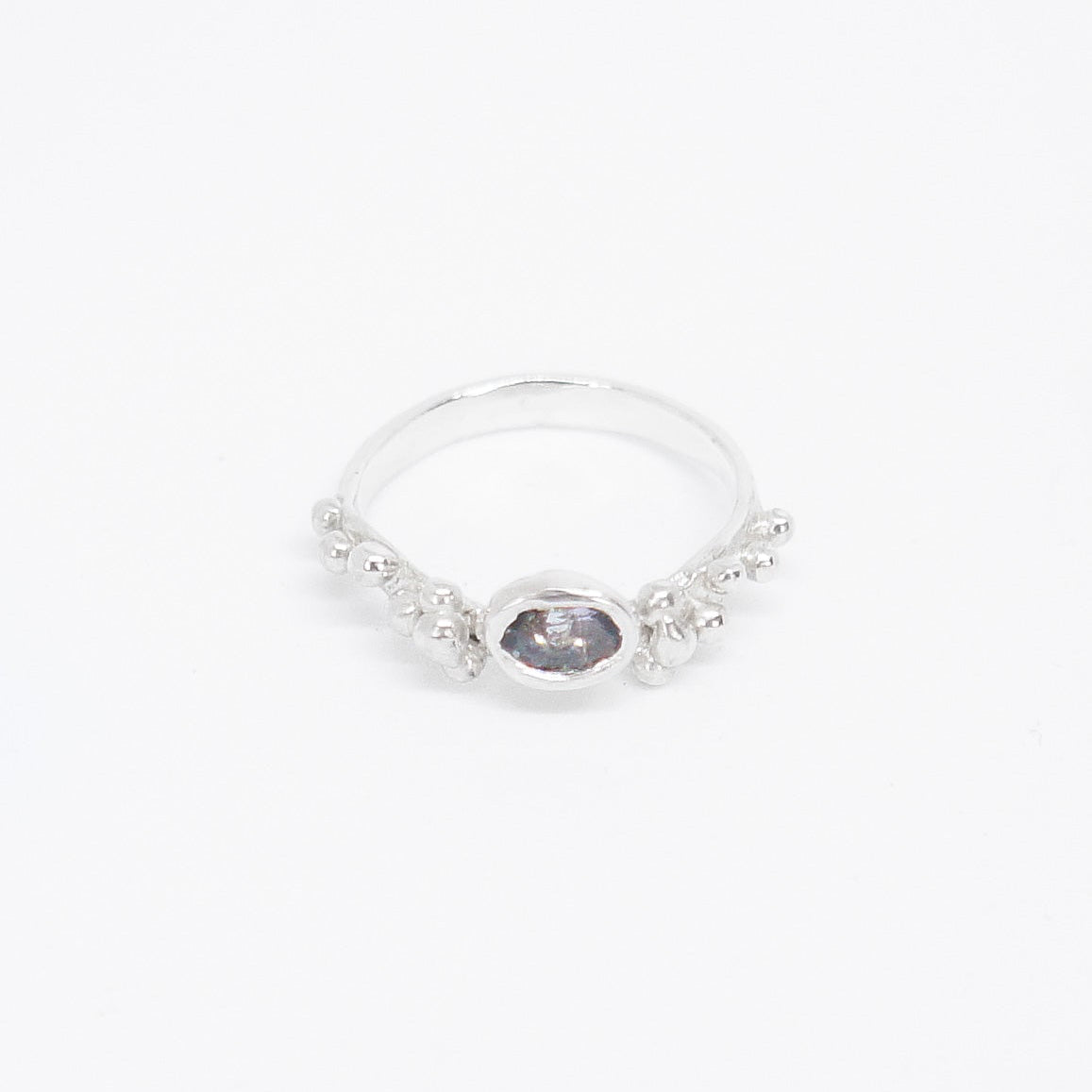 Silver ring with a dark gemstone on a white background