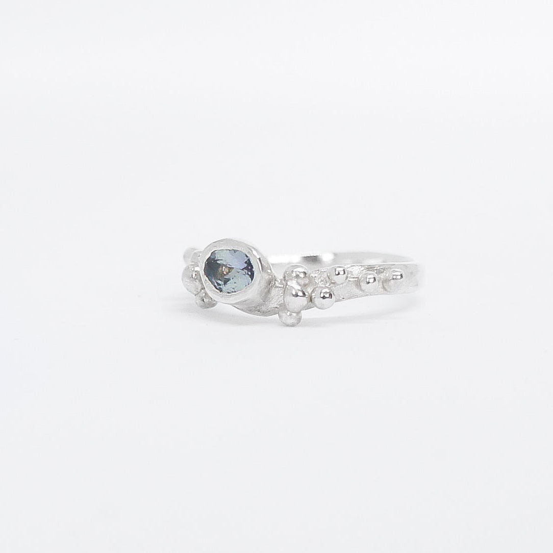 Silver ring with a blue gemstone on a white background