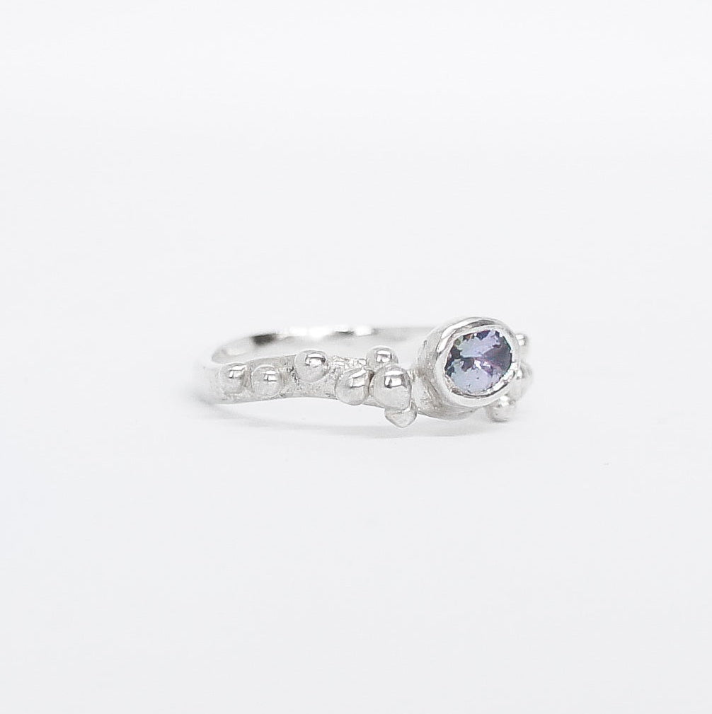 Silver ring with a purple gemstone on a white background