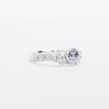 Silver ring with a purple gemstone on a white background