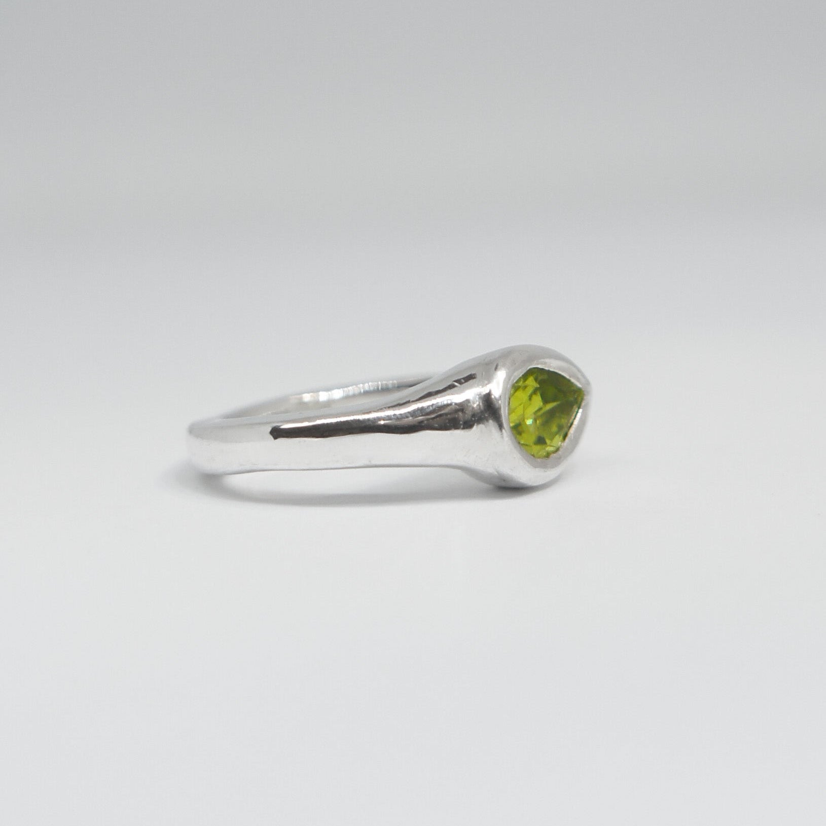 Silver ring with a green gemstone on a white background