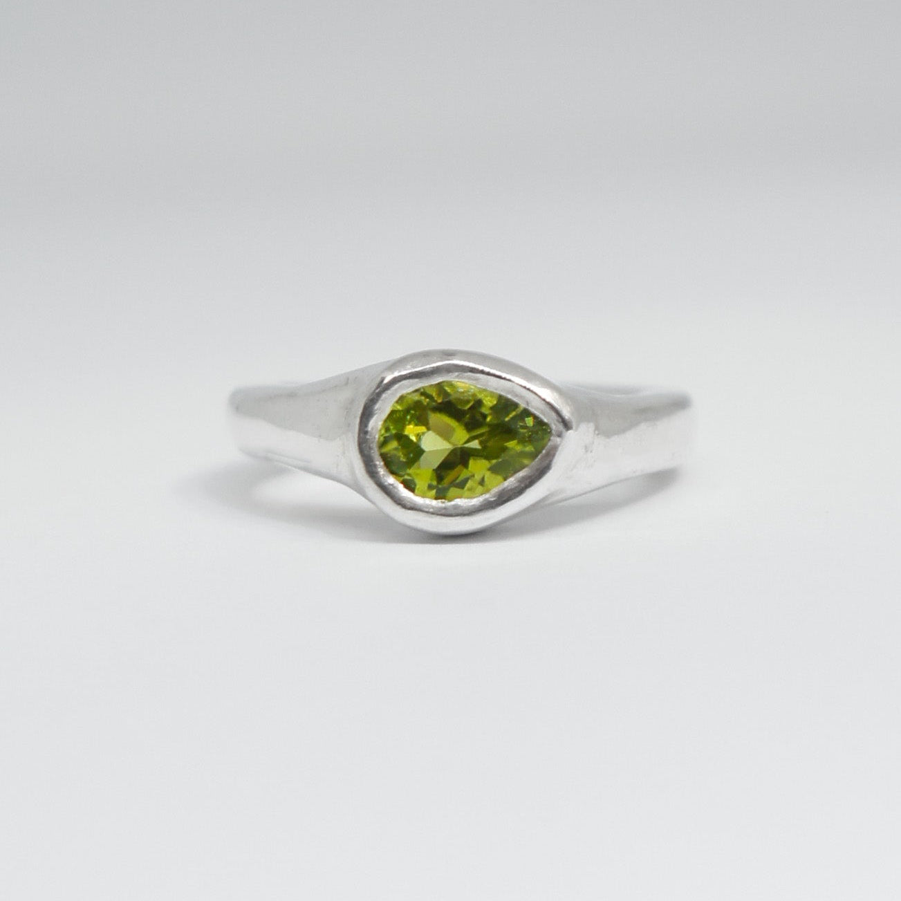 Silver ring with a green gemstone on a white background