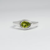 Silver ring with a green gemstone on a white background