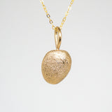 Gold pendant necklace on a light gray background