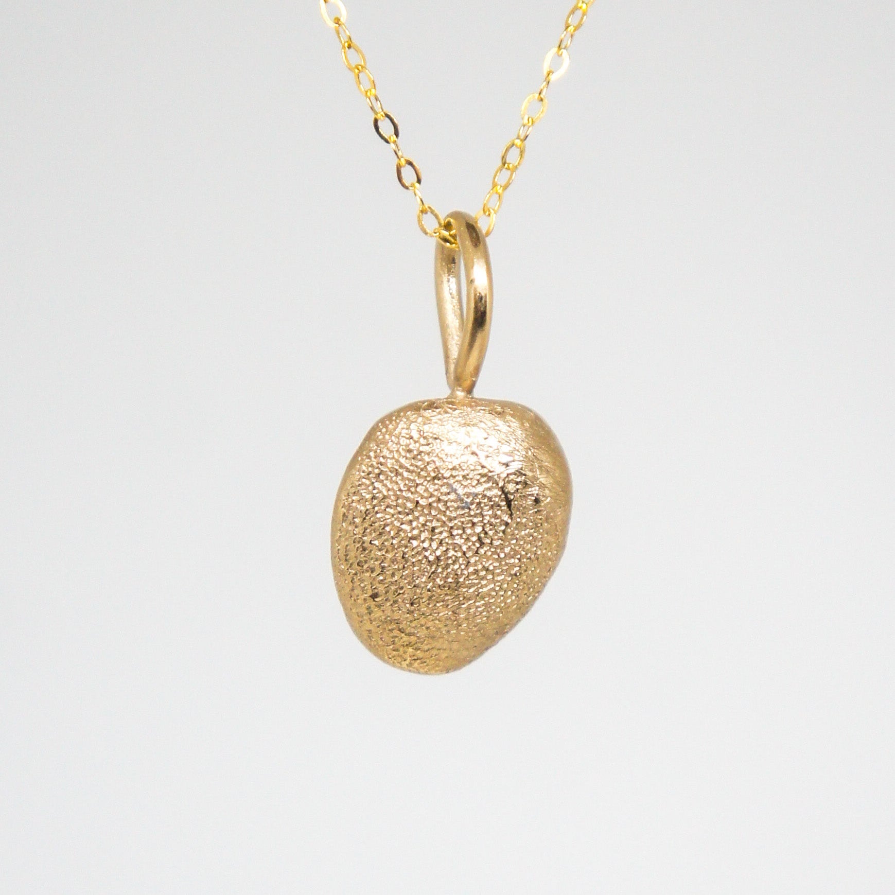Gold pendant necklace on a light gray background