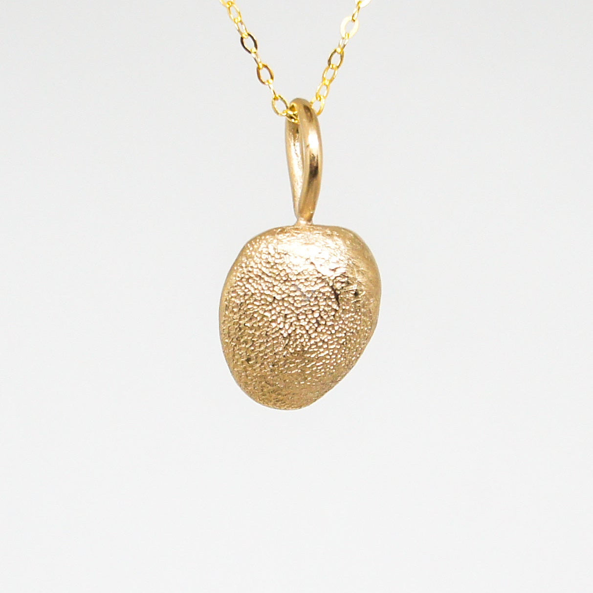 Gold pendant necklace on a light gray background