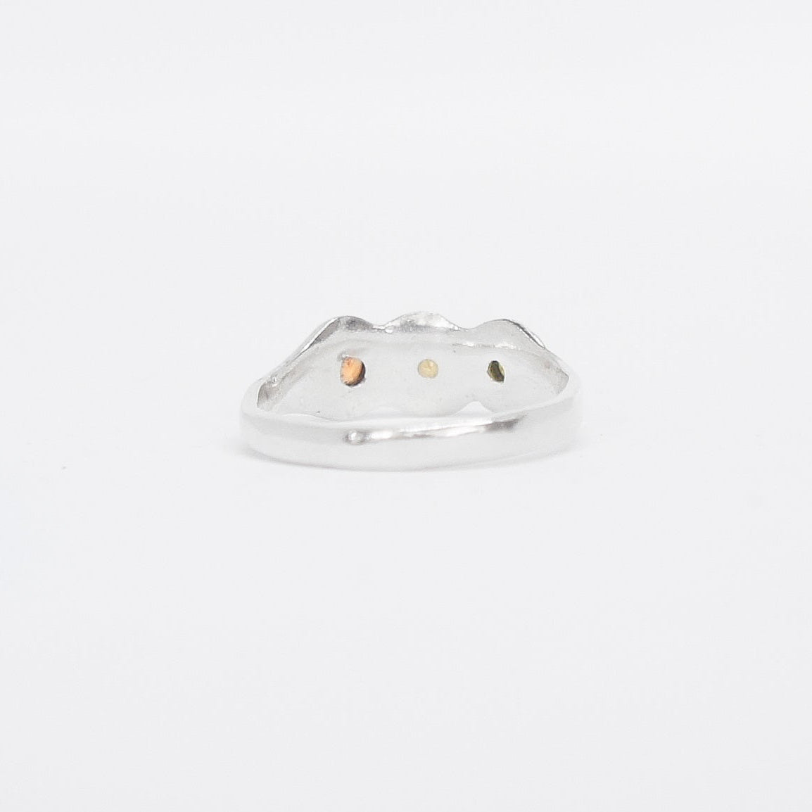 Silver ring with three colored stones on a white background