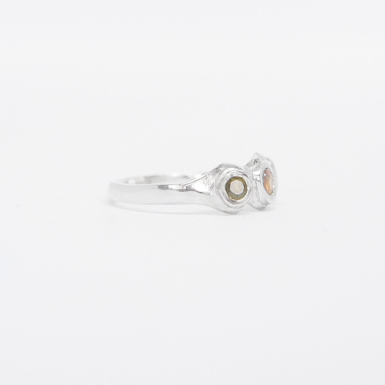 Silver ring with three colored stones on a white background