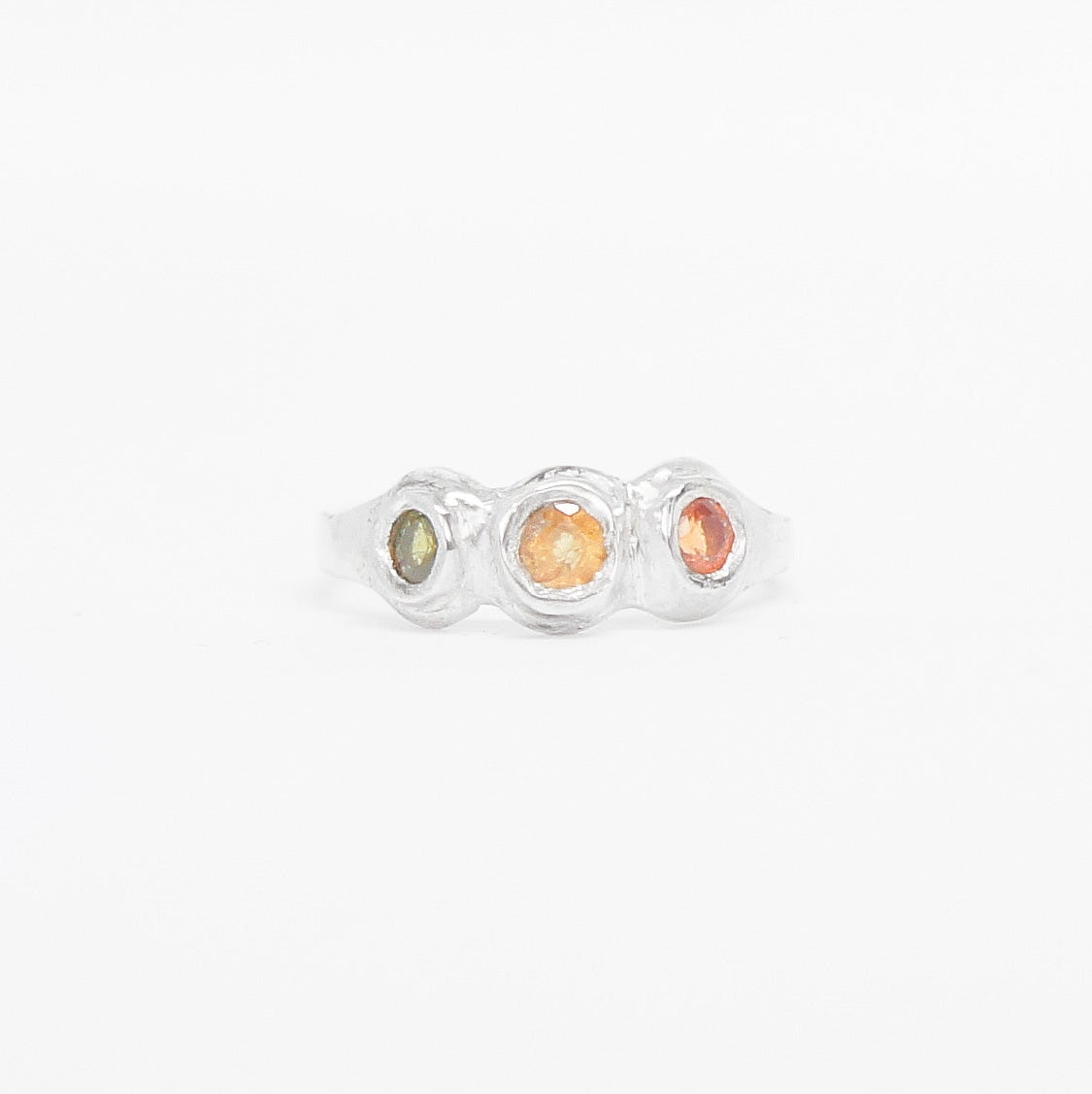 Silver ring with three colored stones on a white background