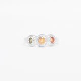 Silver ring with three colored stones on a white background