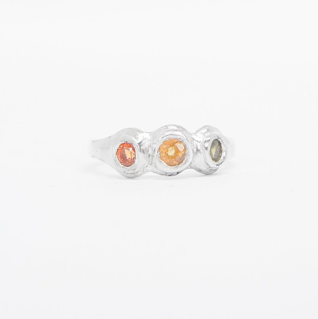 Silver ring with three colored stones on a white background