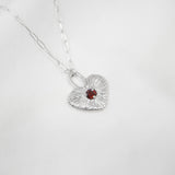 Silver necklace with a heart-shaped pendant on a white background