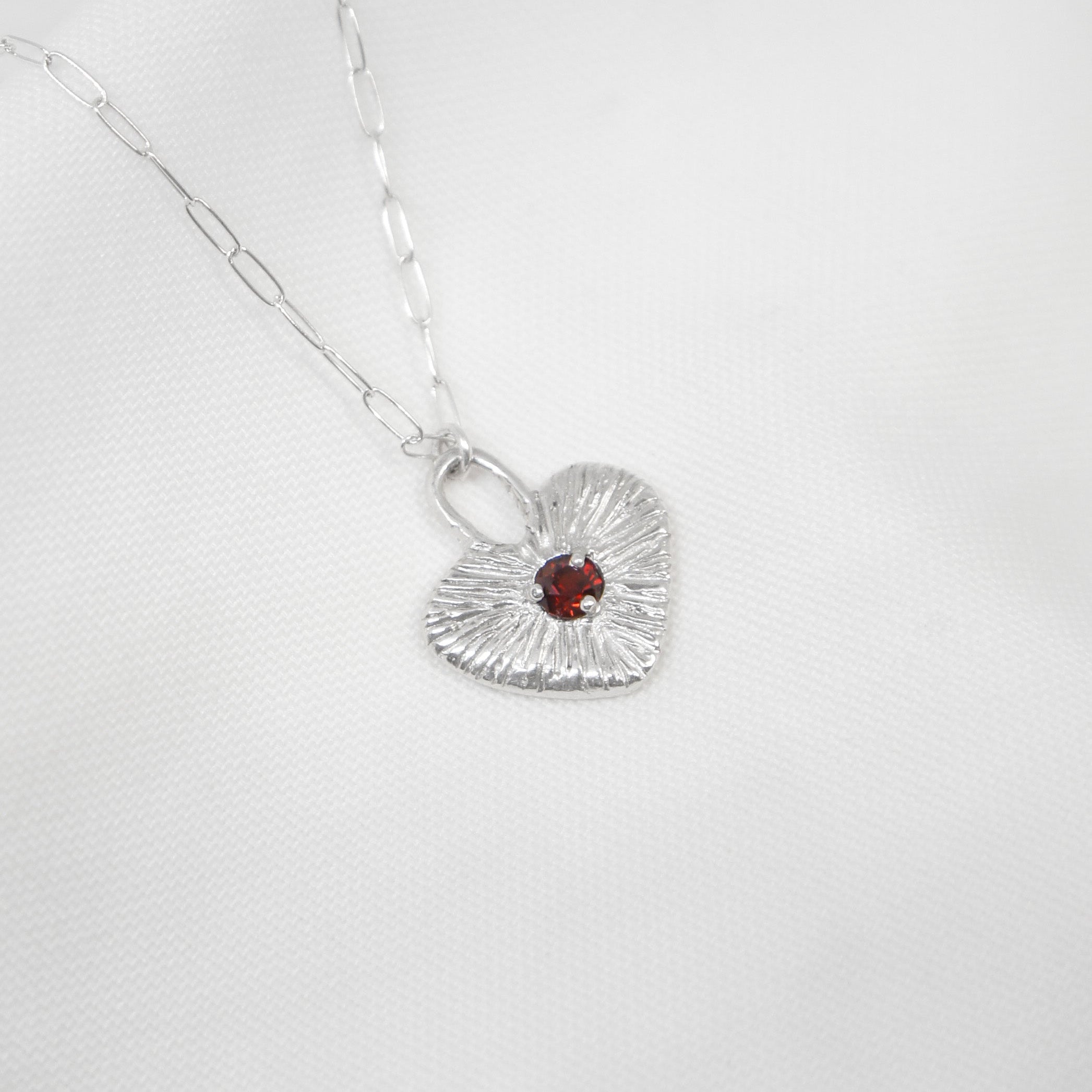 Silver necklace with a heart-shaped pendant on a white background