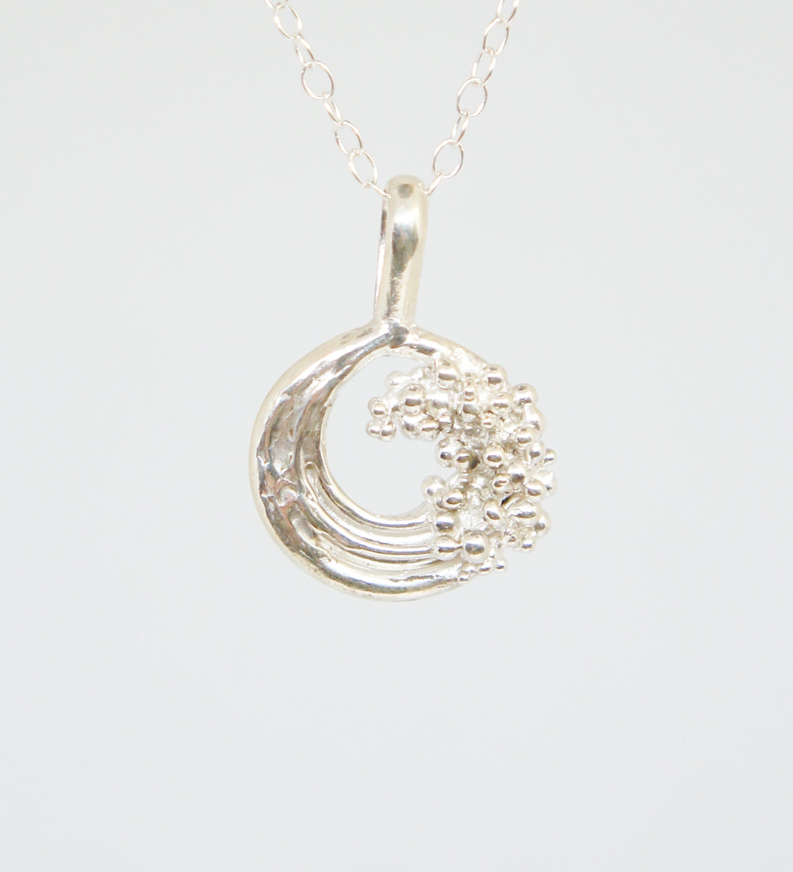 Silver necklace with a crescent moon pendant on a white background