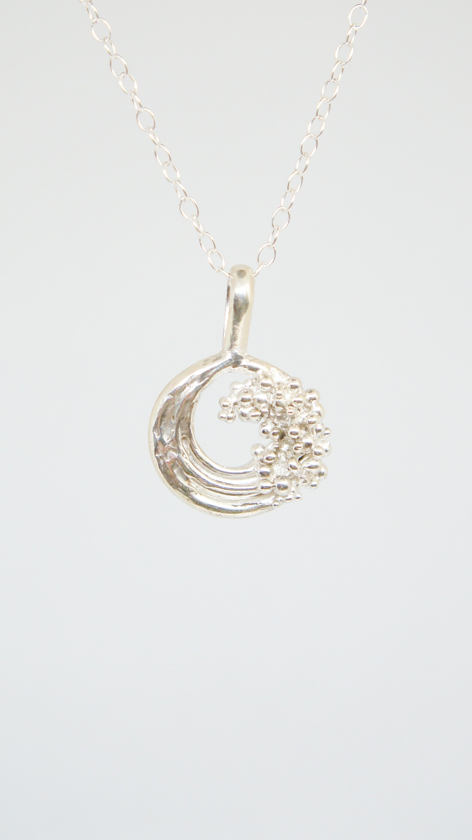 Silver necklace with a crescent moon pendant on a white background
