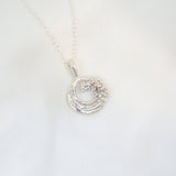 Silver necklace with a circular pendant on a white background