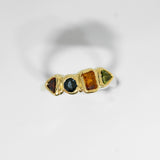 Gold ring with multicolored gemstones on a light gray background