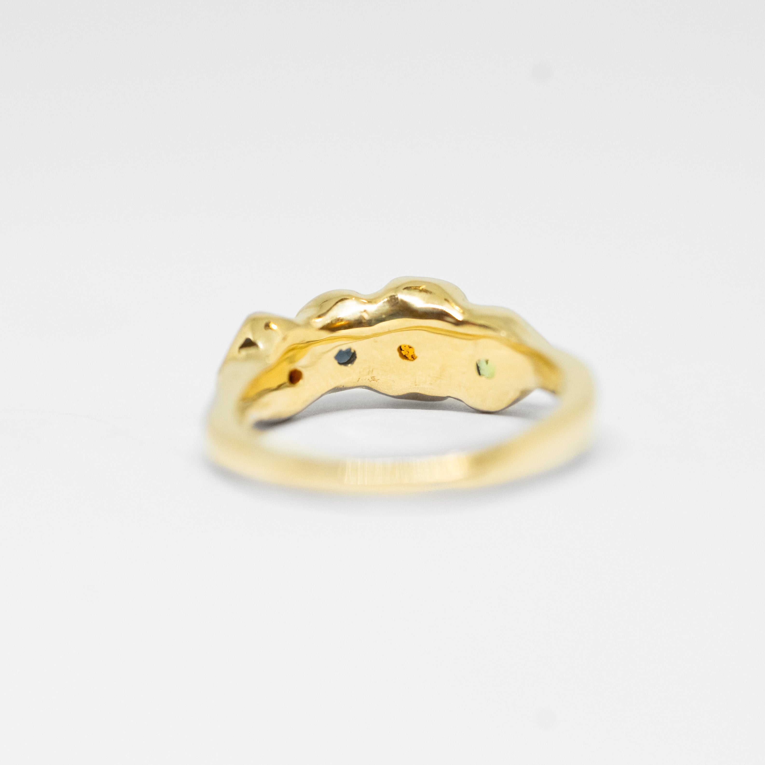 Gold ring with multi coloured gemstone on a light gray background