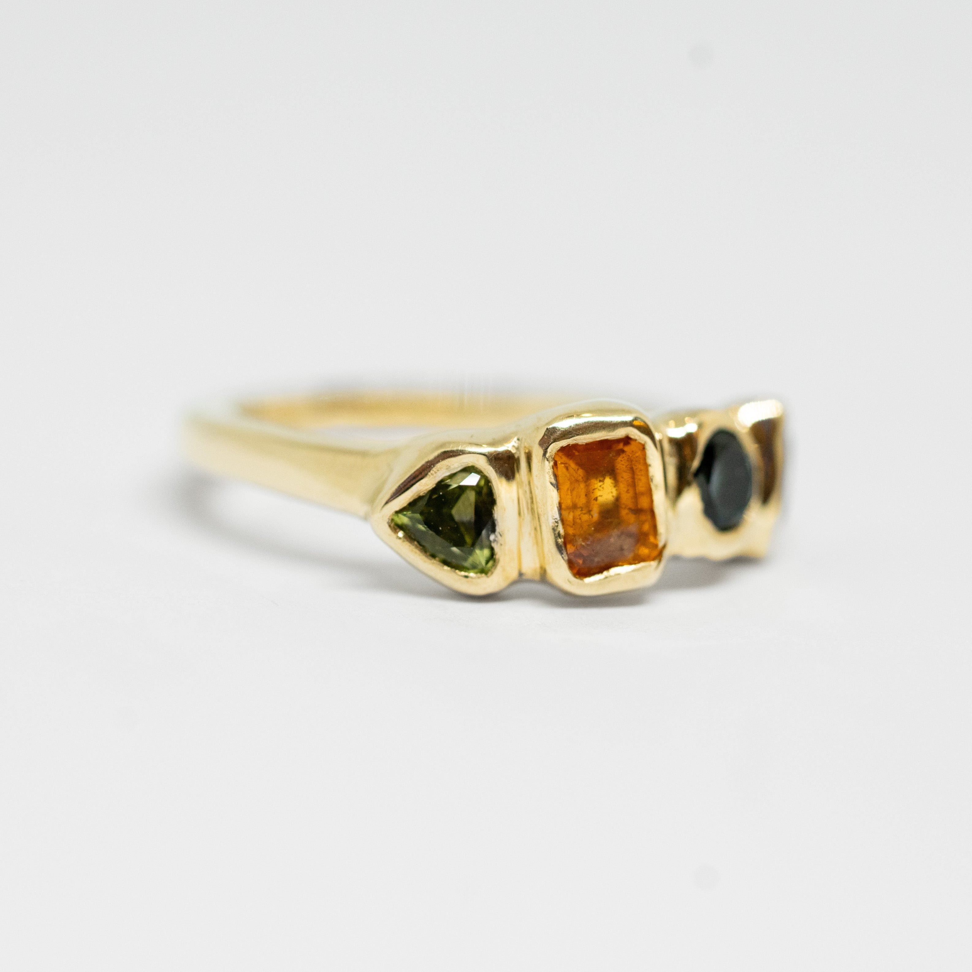 Gold ring with multicolored gemstones on a white background