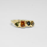 Gold ring with four coloured gemstones on a white background