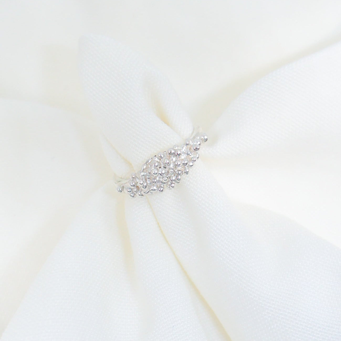 Close-up of a white dress with a decorative belt on a light background