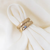 Two gold rings with blue stones on a white fabric background