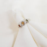 Silver ring with colored stones on a white fabric background